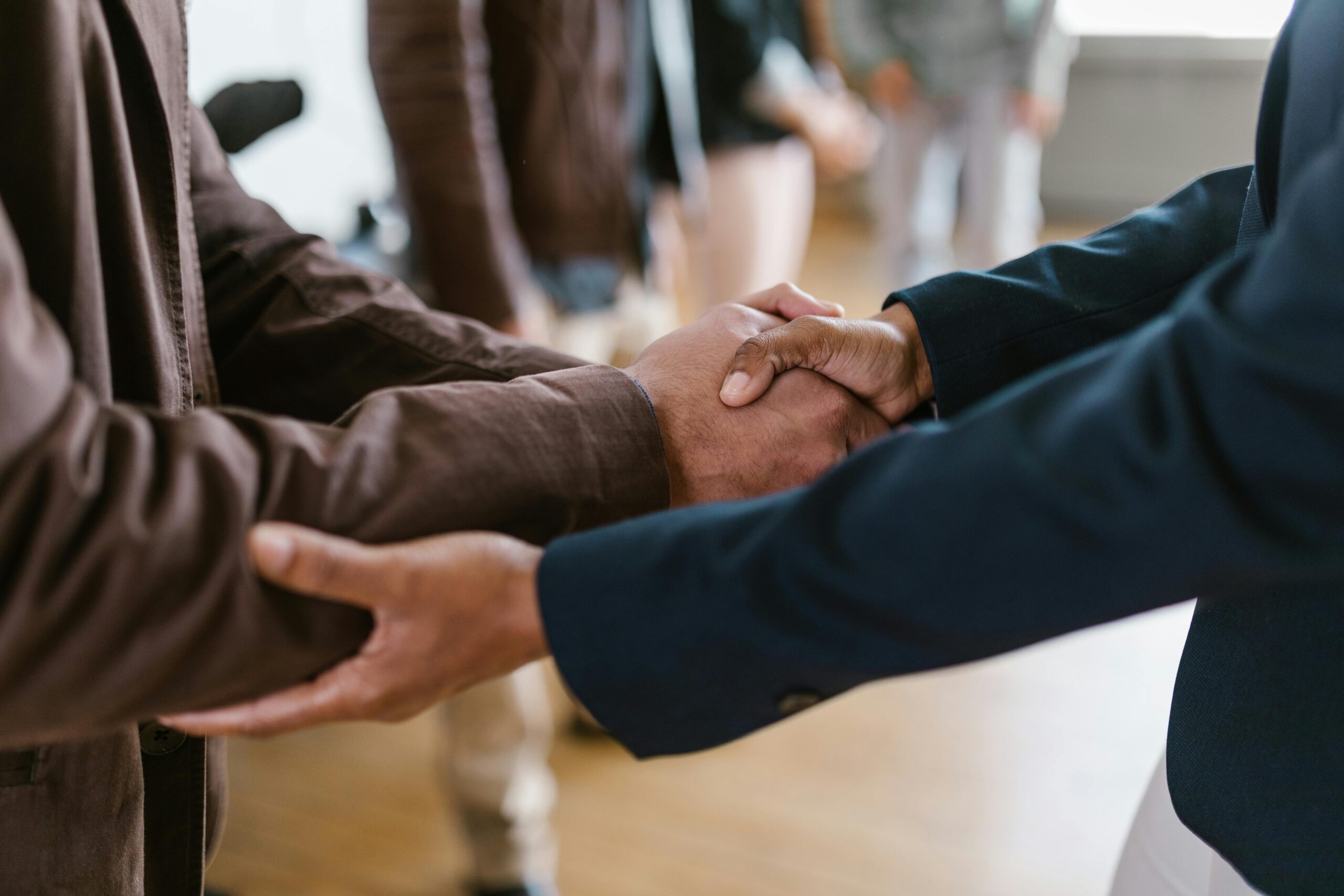 Two individuals shaking hands in a professional setting, symbolizing partnership or agreement.